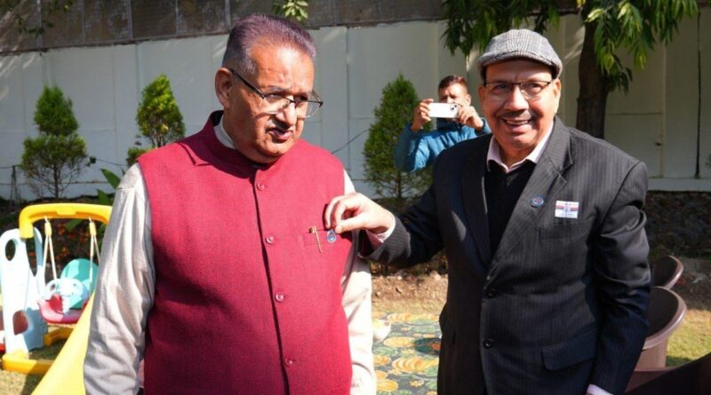 सशस्त्र सेना झंडा दिवस के अवसर पर सैनिक कल्याण मंत्री गणेश जोशी को फ्लैग लगाते विभाग के अधिकारी